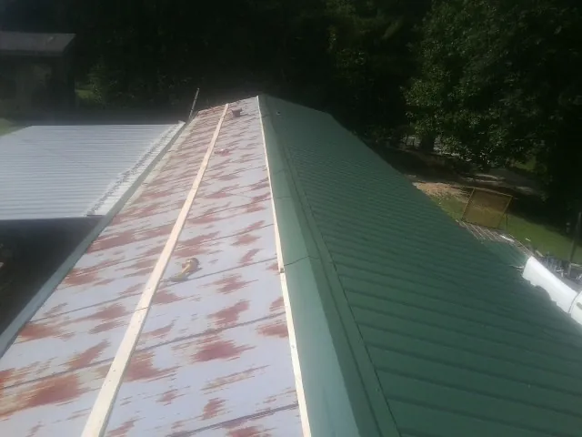 Old rusted panels beside newly installed green metal roofing — Wind Damage Roof Repair by Roofing Brothers in Bradford